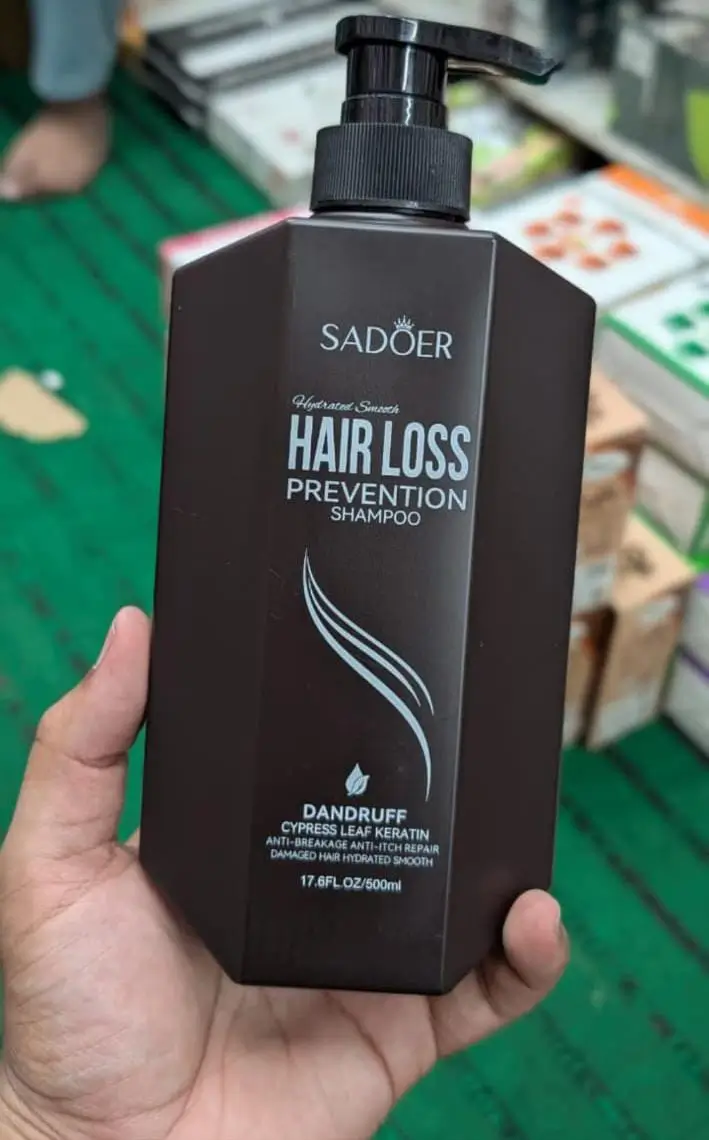 "A person holding a bottle of Sadoer Hair Loss Prevention Shampoo, 500ml, labeled with anti-dandruff and keratin benefits for hydrated and smooth hair