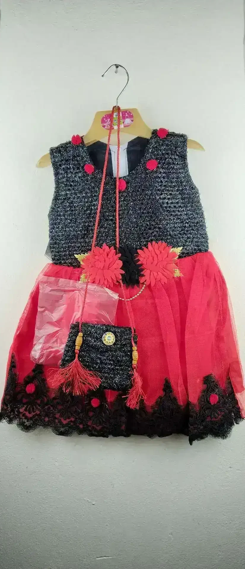Girls Black & Red Party Dress with black glittery bodice, red skirt, floral waist accents, and matching black purse, displayed on hanger against white wall