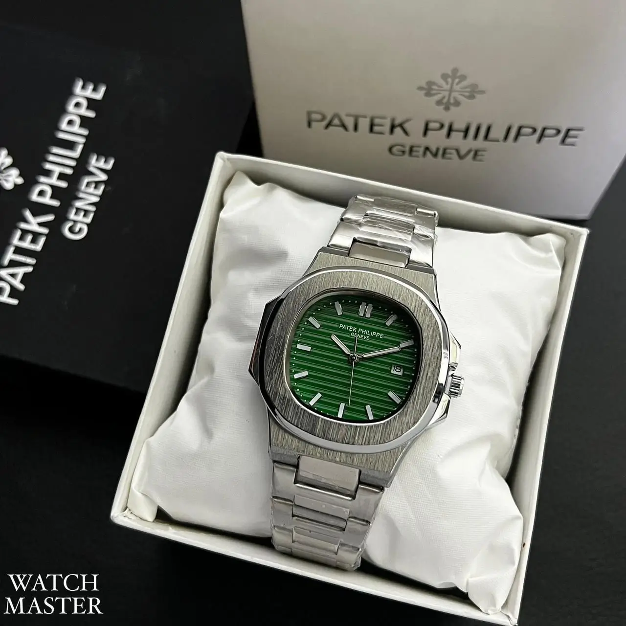 Patek Philippe Nautilus men’s luxury wristwatch with a green dial and silver stainless-steel bracelet, displayed in its original box with Patek Philippe branding in the background.
